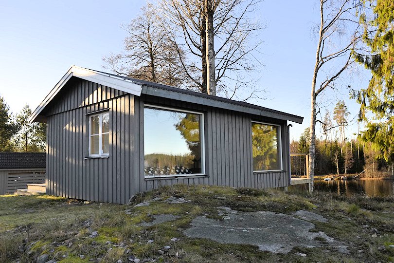 Überraschung: Zum See hin punktet das Gästehaus mit 2 großen Panoramafenstern: 1x Schlafzimmer, 1x Sauna Galeriebild Traumobjekt Sjövik am See Hornbetasjön. Echtes Seeufergrundstück in dramatisch schöner Wasser- und Alleinlage in Småland